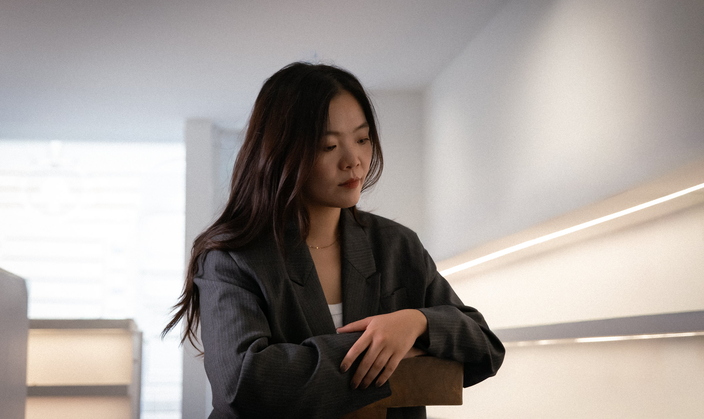 Nina Xu standing in a sunlit corridor, arms folded on a rail